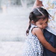 Sad asian little girl hugging her mother leg in vintage color tone