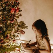 Girl journaling by Christmas Tree
