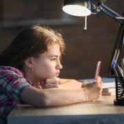 Teenage girl with mobile phone late in evening